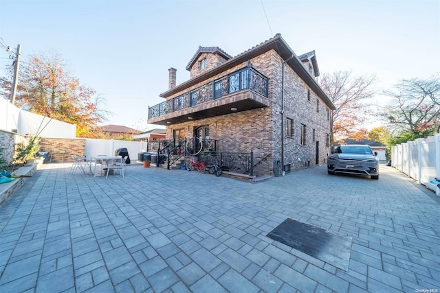 back of house featuring a balcony and a patio