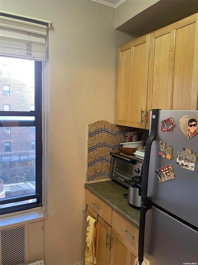 kitchen featuring decorative backsplash, stainless steel fridge, and light brown cabinets