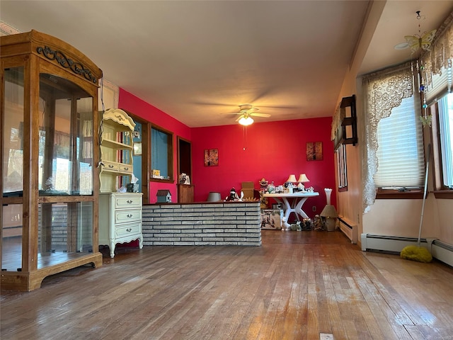 misc room featuring ceiling fan, a baseboard heating unit, and hardwood / wood-style flooring