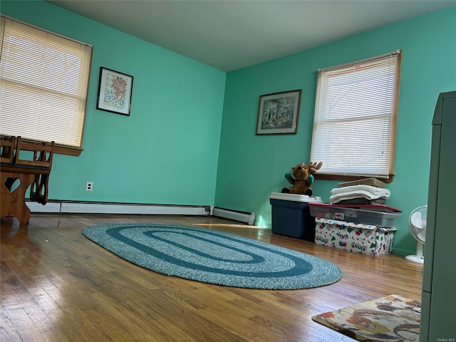 living area featuring wood-type flooring and a baseboard heating unit