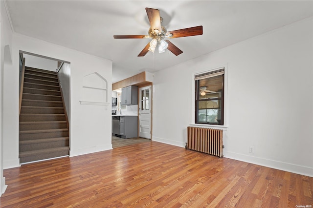 unfurnished living room featuring light hardwood / wood-style flooring, radiator, and ceiling fan