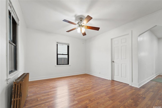 spare room featuring radiator heating unit, ceiling fan, and dark wood-type flooring