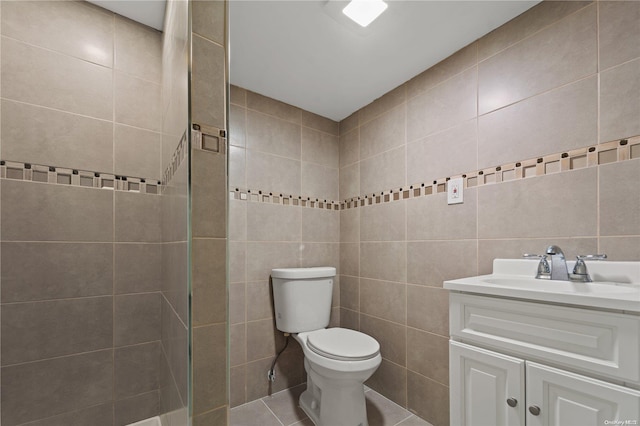 bathroom featuring tile patterned flooring, vanity, toilet, and tile walls