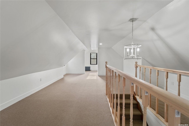 hallway with carpet flooring, a notable chandelier, and vaulted ceiling