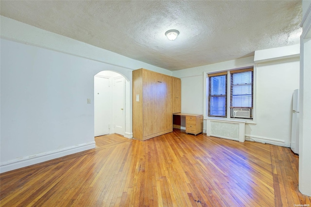 unfurnished room featuring a textured ceiling, light hardwood / wood-style flooring, and cooling unit