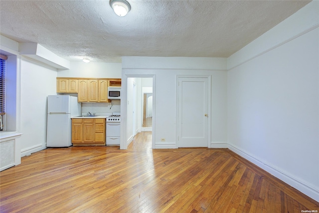 kitchen featuring decorative backsplash, light wood-type flooring, white appliances, and sink