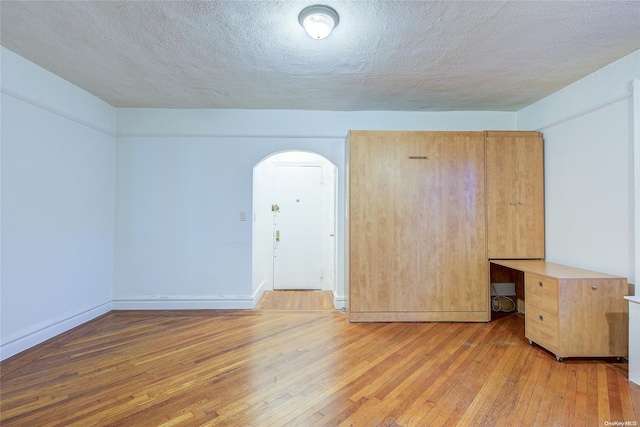 empty room featuring a textured ceiling and light hardwood / wood-style floors