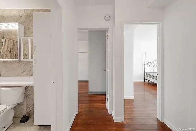 hallway featuring hardwood / wood-style flooring and tile walls