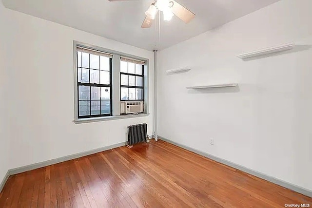 empty room with hardwood / wood-style flooring, ceiling fan, and radiator heating unit