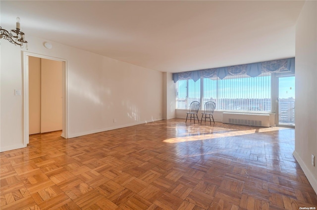 empty room with radiator heating unit, parquet flooring, and a chandelier