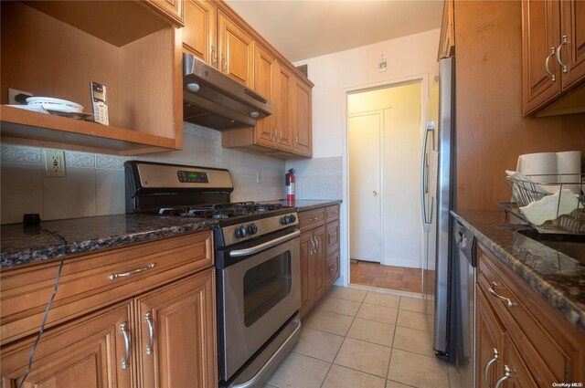 166-25 Powells Cove Blvd Unit 10G, Whitestone, NY 11357 - kitchen featuring appliances with stainless steel finishes, under cabinet range hood, brown cabinets, backsplash, and dark stone countertops
