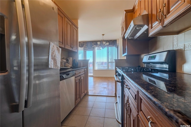 166-25 Powells Cove Blvd Unit 10G, Whitestone, NY 11357 - kitchen with appliances with stainless steel finishes, tasteful backsplash, under cabinet range hood, light tile patterned floors, and brown cabinets