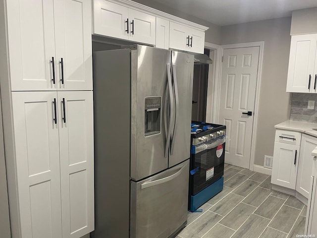 kitchen featuring white cabinetry, stainless steel appliances, and decorative backsplash