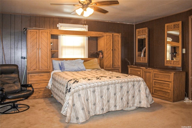 bedroom with carpet flooring, ceiling fan, and wood walls