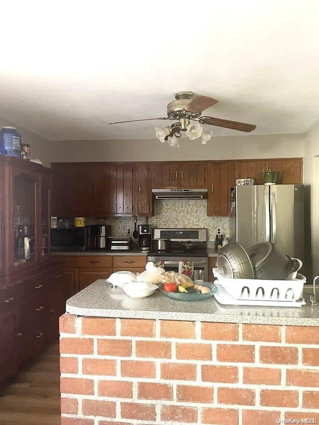 kitchen with decorative backsplash, a center island, stainless steel appliances, and dark wood-type flooring