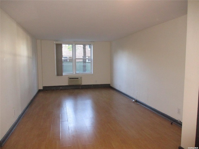 empty room with hardwood / wood-style flooring and a wall unit AC