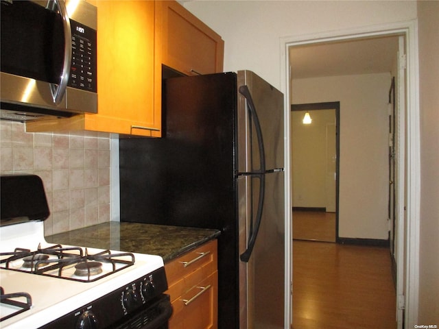 kitchen featuring decorative backsplash, wood-type flooring, white range with gas cooktop, and dark stone counters