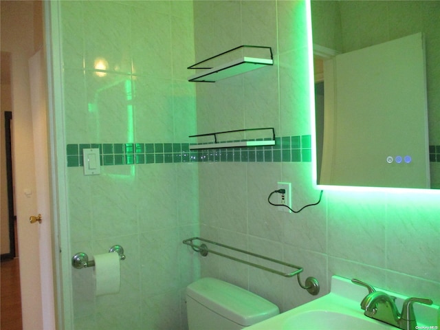 bathroom featuring toilet, tile walls, and sink