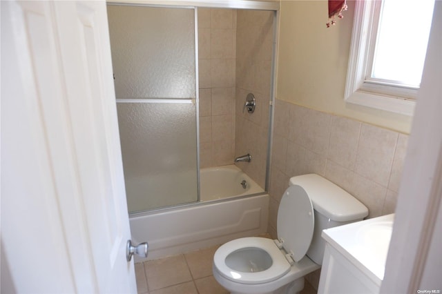 full bathroom featuring enclosed tub / shower combo, tile patterned floors, toilet, vanity, and tile walls