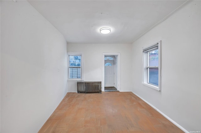 empty room featuring hardwood / wood-style flooring, plenty of natural light, and radiator