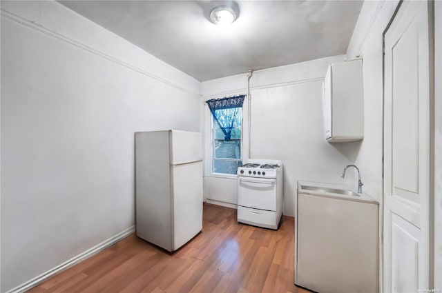 kitchen with sink, white appliances, and light wood-type flooring