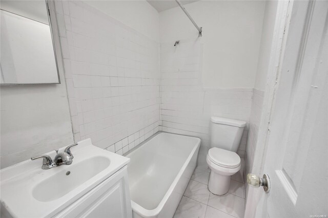 bathroom with vanity, toilet, and tile walls