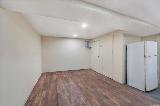 basement with dark hardwood / wood-style floors and white refrigerator