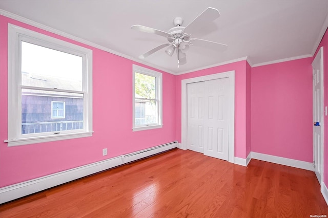 unfurnished bedroom featuring ceiling fan, a baseboard heating unit, wood-type flooring, a closet, and ornamental molding