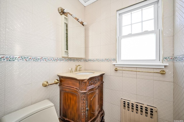 bathroom featuring radiator heating unit, vanity, tile walls, and toilet