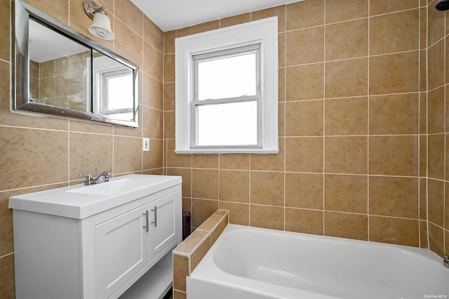 bathroom with a bathing tub, vanity, and tile walls