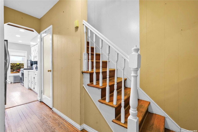 stairs with wooden walls and hardwood / wood-style floors