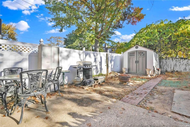 view of patio featuring grilling area, an outdoor fire pit, and a storage unit