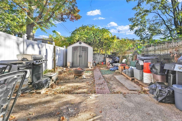 view of yard with a storage shed and an outdoor fire pit