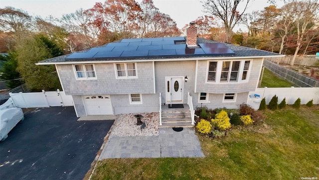 back of house featuring solar panels, a garage, and a lawn