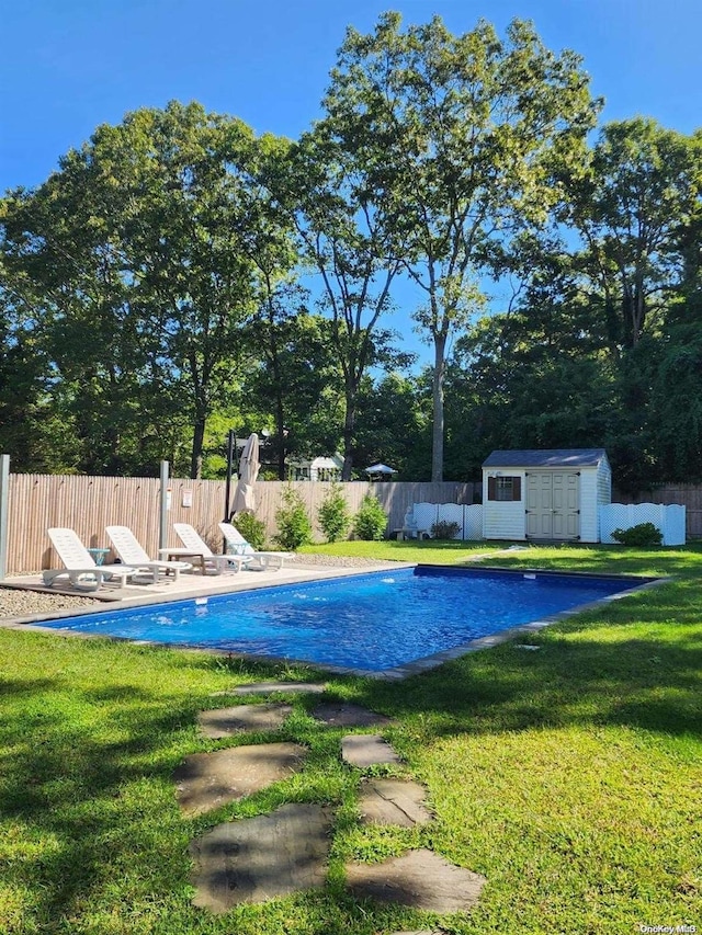 view of swimming pool with a lawn and an outbuilding