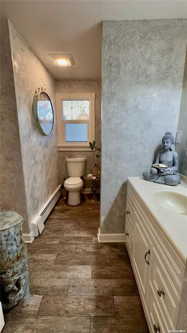 bathroom featuring vanity, toilet, wood-type flooring, and a baseboard heating unit