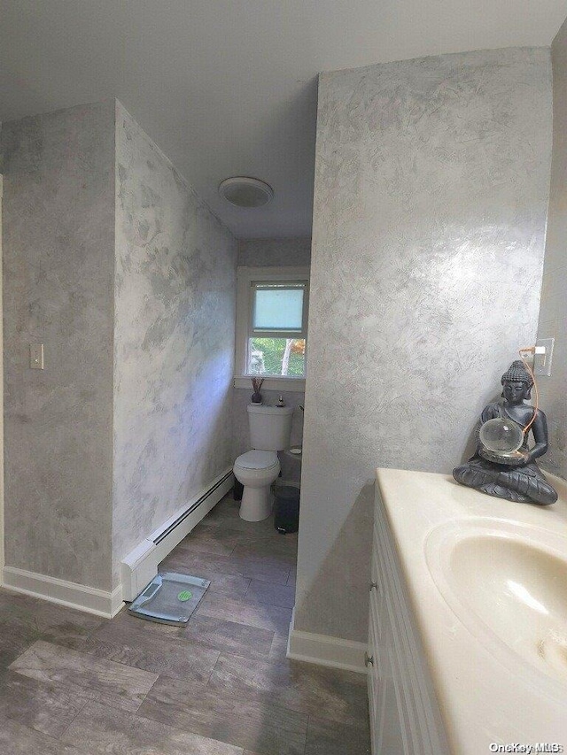 bathroom with toilet, vanity, and a baseboard heating unit