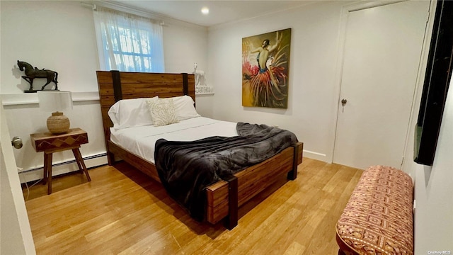 bedroom with light wood-type flooring and a baseboard heating unit