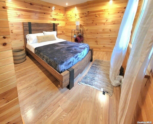 bedroom featuring wooden walls and hardwood / wood-style floors