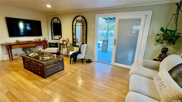 living room featuring light hardwood / wood-style floors, baseboard heating, and ornamental molding