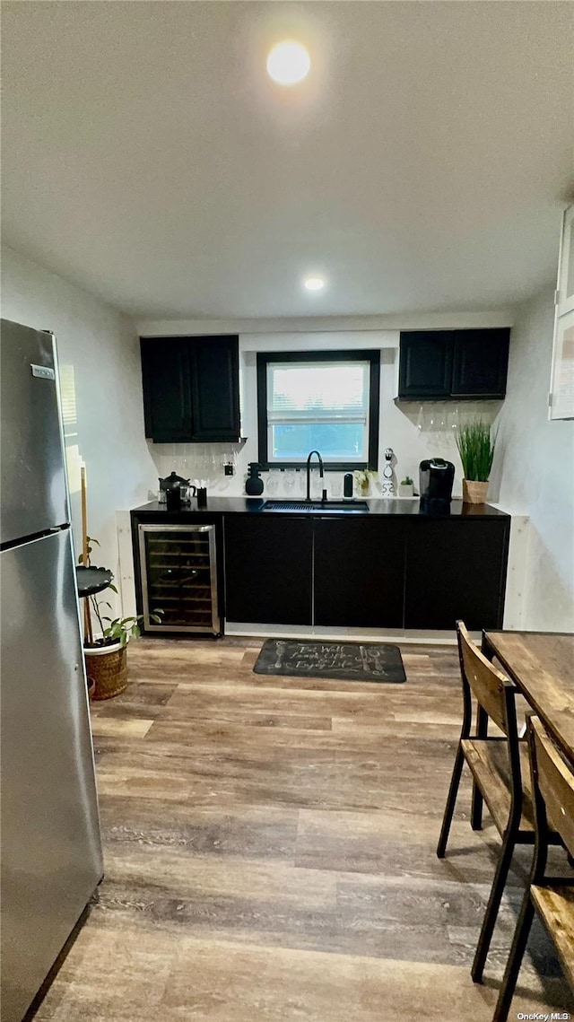 kitchen with wine cooler, stainless steel fridge, sink, and light hardwood / wood-style floors