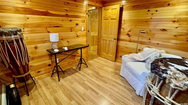 sitting room with light hardwood / wood-style floors and wooden walls