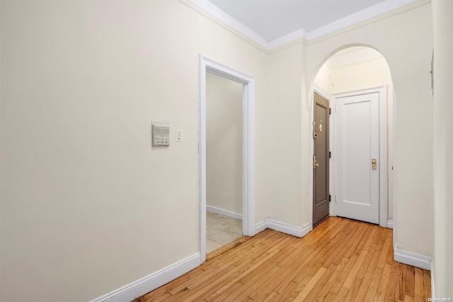 hallway featuring light wood-type flooring and ornamental molding