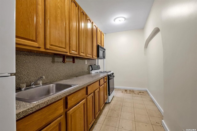 kitchen with stove, tasteful backsplash, white fridge, and sink