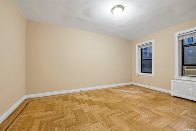 empty room featuring cooling unit, radiator heating unit, and light parquet flooring