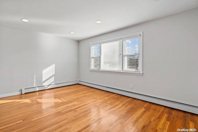 unfurnished room featuring a baseboard radiator and light wood-type flooring