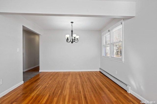 spare room featuring hardwood / wood-style flooring, a baseboard radiator, and an inviting chandelier