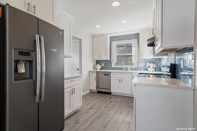 kitchen featuring appliances with stainless steel finishes, sink, backsplash, white cabinets, and light wood-type flooring