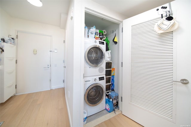 laundry area featuring stacked washing maching and dryer and light hardwood / wood-style flooring