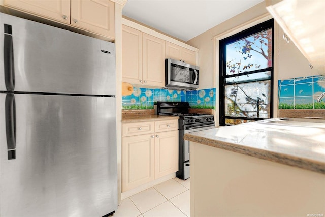 kitchen featuring backsplash, cream cabinets, light tile patterned flooring, and stainless steel appliances